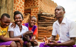 Young adults in Africa sitting in a circle talking and smiling.